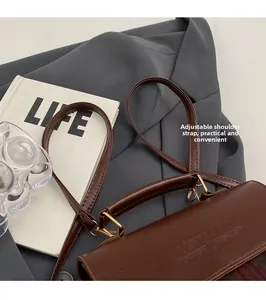 Detail of vintage brown faux leather handbag with adjustable strap and embossed text
