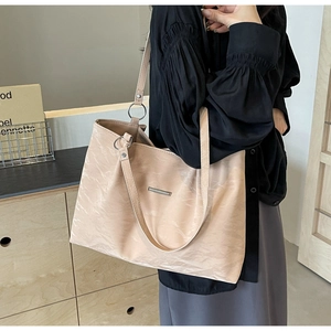 Detail of light pink tote bag featuring unique pleated texture and minimalist metal bar