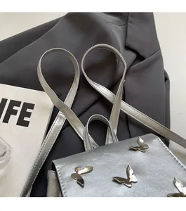 Detail of silver metallic backpack featuring butterfly charms and sleek shoulder straps