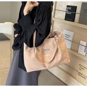 Detail of beige pleated tote bag showing wrinkled texture and silver strap rings