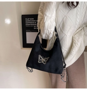 Detail of black suede shoulder bag with gold butterfly embroidery and metal chains