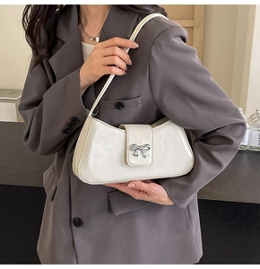 Details der cremeweißen Kunstledertasche mit silberner Schleife als Schultertasche