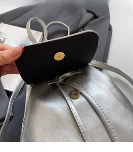 Detail of silver metallic backpack featuring a secure magnetic snap and drawstring closure