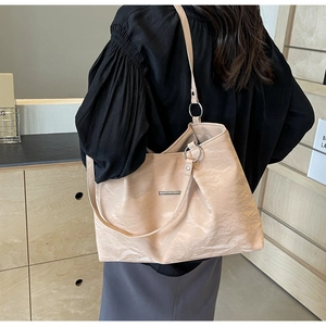 Detailed view of beige soft leather tote bag with silver ring shoulder strap connector