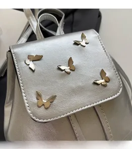 Detailed macro view of silver faux leather backpack flap with five gold butterfly ornaments