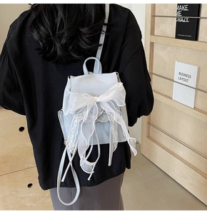 Detail showing a light blue ballet-style mini backpack with a large white lace bow detail