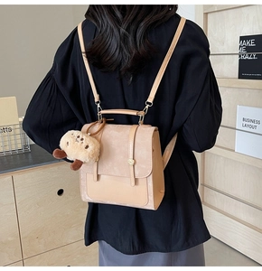 Detailansicht eines beigen Vintage-Rucksacks mit glatten Lederbesätzen und Plüschanhänger