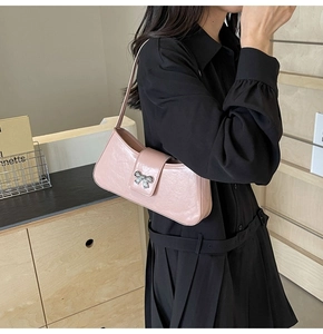 Detail der rosa Baguette-Tasche mit silberner Schleife getragen von Model in Schwarz