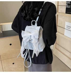 Detail of light blue backpack featuring a large translucent organza bow and drawstring