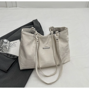 Detail of white textured leather tote bag with silver logo plate and ring buckle hardware