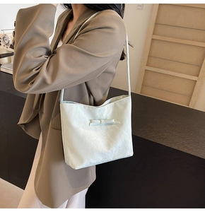 Gros plan du sac seau à nœud vert clair avec texture plissée porté par un modèle