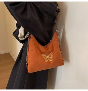 Detail of orange hobo bag with gold butterfly embroidery and leather chain strap