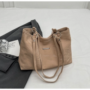 Detail of soft wrinkled leather texture and silver metal plaque on apricot tote bag