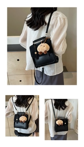 Details einer schwarzen matten Ledertasche mit goldener Schnalle und Plüsch-Anhänger