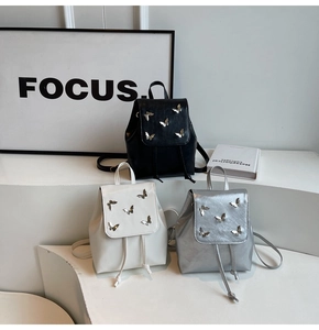 Detailed view of mini butterfly backpacks in black, white, and silver on display stands