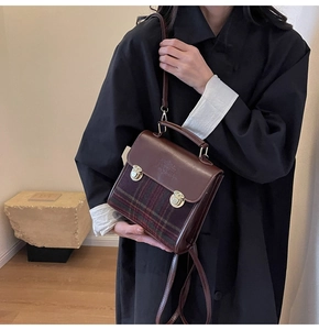 Detailed view of vintage crossbody bag with brown leather and green plaid fabric