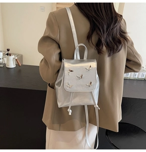Detail view of silver PU leather backpack with decorative metallic butterfly motifs