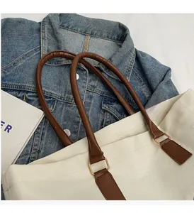 Detalle de las asas de cuero PU marrón y hebillas doradas en un bolso de lona