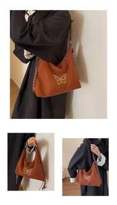 Detail of butterfly embroidery and chain strap on a vintage suede hobo shoulder bag