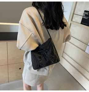 Détail du sac à bandoulière noir brillant plissé avec nœud et fine sangle d'épaule