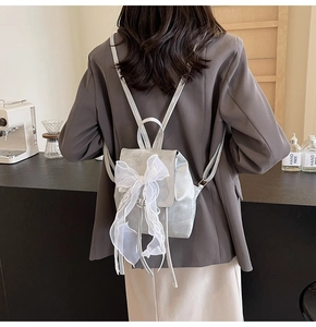 Silver-grey mini backpack with large white lace bow shown on a female model