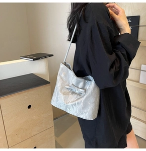 Détail du sac seau plissé gris argenté avec décoration en nœud et finition nacrée