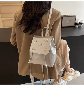 Detail of silver metallic backpack featuring metal butterfly rivets and drawstring closure