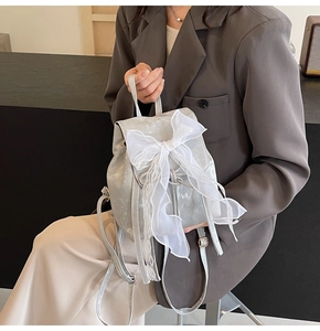 Detail of silver metallic mini backpack featuring a large white lace bow decoration