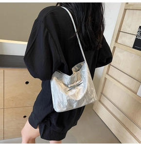 Sac à bandoulière argenté métallisé avec détail de nœud papillon porté par le mannequin