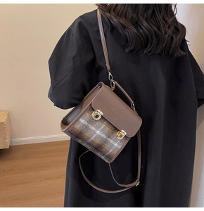 Detail of vintage plaid shoulder bag with brown leather trim and metallic buckles