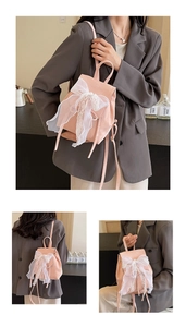 Close-up of pink ballerina style backpack featuring a large white lace ribbon bow detail