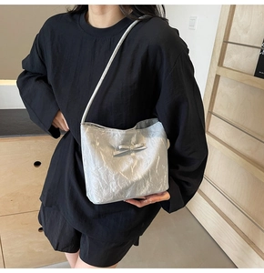 Détail d'un sac seau argenté avec texture métallique froissée et détail de nœud