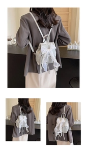 Detail of silver metallic mini backpack with large white lace bow and drawstring closure
