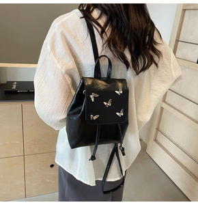 Detail of black leather backpack with silver butterfly accents and drawstring closure