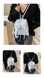 Detail of light blue ballet-style backpack featuring a large lace bow and drawstring