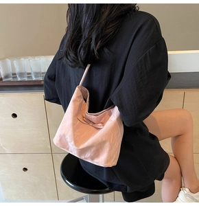 Vue détaillée du sac seau rose à nœud avec texture plissée porté à l'épaule