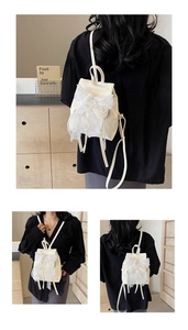 Detail of white ballet-style backpack featuring a large lace bow and elegant ribbon design