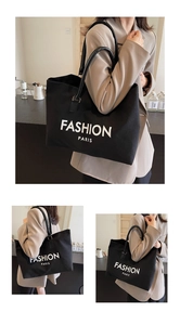 Detail of large black tote bag with white FASHION PARIS print and leather handles