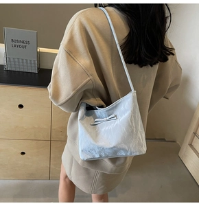 Sac bandoulière bleu clair plissé avec nœud porté par un mannequin dans un décor épuré