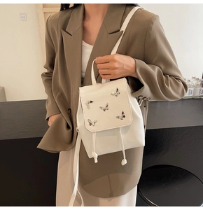White leather backpack with silver butterfly accents shown on female model in a side view