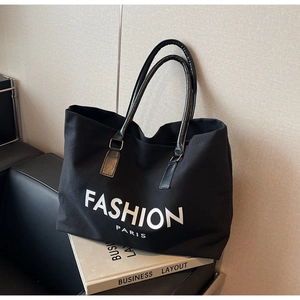 Detail of metal ring buckles and logo print on black canvas tote bag