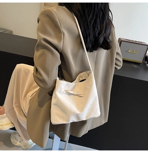 Sac seau chic à nœud crème porté avec une tenue professionnelle kaki stylée