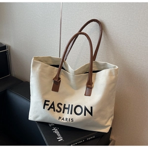 Close-up of canvas tote bag with brown leather handles and Fashion Paris print
