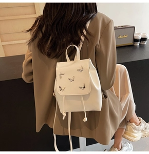 Detail of off-white mini backpack featuring 3D metal butterflies and drawstring closure