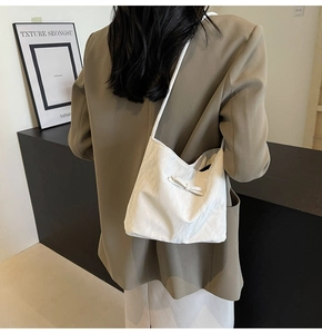 Détail du sac seau plissé blanc avec nœud porté à l'épaule par le mannequin