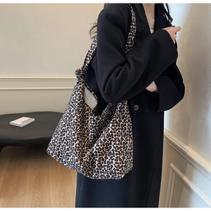Close-up of stylish leopard print canvas tote bag shown on a model in a natural setting