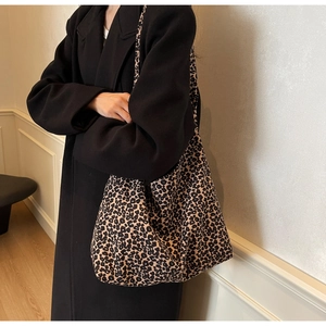 Detailed view of large leopard print tote bag being worn by a model in black coat