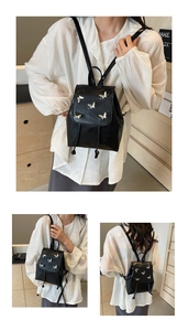 Detail view of mini black faux leather backpack with silver butterfly accents and drawstring