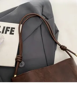 Detail of dark brown leather tote with knotted shoulder strap and embossed lettering