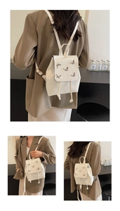 Detailed view of white mini backpack with silver butterfly buckles and drawstring closure